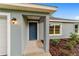 Close-up of the home's entry featuring a stylish blue door, modern lighting, and attractive landscaping at 15673 Sw 37 Cir, Ocala, FL 34482