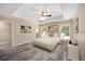 Cozy main bedroom with tray ceilings, modern flooring, a ceiling fan, and bright windows at 15673 Sw 37 Cir, Ocala, FL 34482