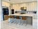 Modern kitchen with stainless steel appliances, large center island with seating, and tile backsplash at 16832 Bolsena Dr, Bella Collina, FL 34756