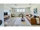 Bright living room with a brown leather sofa, dining area, and light gray wood flooring at 16832 Bolsena Dr, Bella Collina, FL 34756