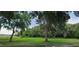Lush backyard with mature trees and a grassy area leading to a natural wooded landscape at 11990 Se 112Th Avenue Rd, Belleview, FL 34420