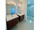 Modern bathroom with dual vanities, sleek fixtures, and a glass shower enclosed with marble-patterned tile at 1314 Congo Ct, Poinciana, FL 34759