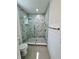Modern bathroom featuring a glass-enclosed shower with marble-patterned tile and herringbone-patterned floor at 1314 Congo Ct, Poinciana, FL 34759