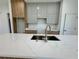 Modern kitchen island with marble countertop, stainless steel sink and faucet, and wood paneled cabinets at 1314 Congo Ct, Poinciana, FL 34759