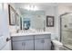 Bright bathroom featuring a double vanity, gray cabinets, and a glass-enclosed shower at 2549 Penguin Blvd, Davenport, FL 33837