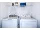 Bright laundry room featuring a modern washer and dryer, with a white wire shelf for storage at 2549 Penguin Blvd, Davenport, FL 33837