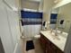 Cozy bathroom features tile flooring, a vanity with marble countertop, and a shower with a blue decorative curtain at 3345 Tesoro Cir, New Smyrna Beach, FL 32168