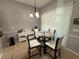 Bright dining area features a round glass table, four chairs, a modern chandelier, and natural light through vertical blinds at 3345 Tesoro Cir, New Smyrna Beach, FL 32168