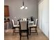 Bright dining area features a round glass table, four chairs, a modern chandelier, and natural light through vertical blinds at 3345 Tesoro Cir, New Smyrna Beach, FL 32168
