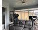 This sunroom features a treadmill, large windows with shades, a ceiling fan, and a gray leather sofa at 3345 Tesoro Cir, New Smyrna Beach, FL 32168