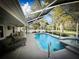 Beautiful screened-in pool and spa with outdoor seating surrounded by a manicured lawn and landscaping at 9233 Tom Moore Rd, Lakeland, FL 33810
