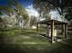 Well house on a large lawn with mature trees and blue sky at 9233 Tom Moore Rd, Lakeland, FL 33810
