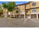 View of the townhome exteriors with stucco facade, garages, and well-maintained landscaping at 6121 Metrowest Blvd # 103, Orlando, FL 32835