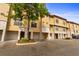 View of the townhome exteriors with stucco facade, garages, and well-maintained landscaping at 6121 Metrowest Blvd # 103, Orlando, FL 32835