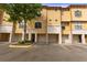 View of the townhome exteriors with stucco facade, garages, and well-maintained landscaping at 6121 Metrowest Blvd # 103, Orlando, FL 32835