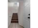 View of carpeted stairs with white walls, a small window and tile flooring leading to the upper level at 6121 Metrowest Blvd # 103, Orlando, FL 32835