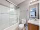 Clean bathroom showcasing a tub with sliding glass doors, toilet, and single sink vanity at 2634 Andros Ln, Kissimmee, FL 34747