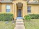 Inviting townhome front door and stone steps lead to a gray door with trim and welcoming front garden at 2634 Andros Ln, Kissimmee, FL 34747