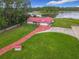 Aerial view of a home with a red metal roof, a long driveway, and a lakeside backyard at 318 Mitnik Dr, Deltona, FL 32738