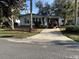 Charming single-story home featuring a driveway, carport, landscaped yard, and mature trees at 910 Orchid St, Lady Lake, FL 32159