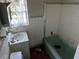 Damaged bathroom with a dirty sink and tub with white tiles and little natural light at 1075 Merritt St, Altamonte Springs, FL 32701