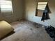 Damaged bedroom featuring plywood floors, and a boarded-up window covered with a black tarp at 1075 Merritt St, Altamonte Springs, FL 32701