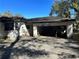 Exterior view of a dilapidated house with a two car garage and overgrown foliage at 1075 Merritt St, Altamonte Springs, FL 32701