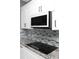 Close up of kitchen showcasing sleek stovetop, modern backsplash, granite countertops, and white cabinets at 1991 Sanderlin Point Loop, Apopka, FL 32703