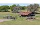 Rustic barn with a weathered roof and adjacent wooden corral, surrounded by a sprawling green pasture at 445 Se 98Th Ave, Webster, FL 33597