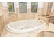 Spacious bathroom with a large soaking tub, gold fixtures, and travertine tile surround at 445 Se 98Th Ave, Webster, FL 33597