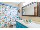 Bathroom with blue vanity, bright patterned shower curtain, and large mirror at 568 Gainsboro St, Deltona, FL 32725