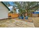 Private backyard featuring a wooden fence, mature trees, and cozy seating area with a grill at 501 Washington Ave, Eustis, FL 32726