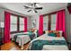 Bright bedroom featuring hardwood floors, two beds, ceiling fan, and colorful curtains and pillows at 501 Washington Ave, Eustis, FL 32726