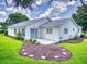 Back exterior of home featuring a small patio and landscaped yard with a stepping stone path at 13729 Se 89Th Ave, Summerfield, FL 34491