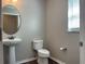 Neutral bathroom with pedestal sink, toilet, round mirror, and a window at 387 Winter Nellis Cir, Winter Garden, FL 34787