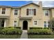 Tan two-story home with manicured landscaping and an inviting arched entryway at 387 Winter Nellis Cir, Winter Garden, FL 34787
