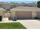 View of the garage door with landscaping and air conditioning units to the side at 387 Winter Nellis Cir, Winter Garden, FL 34787