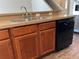 Kitchen featuring wood cabinetry, stainless steel sink, dishwasher, and tan countertops at 387 Winter Nellis Cir, Winter Garden, FL 34787