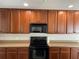 Well-lit kitchen featuring sleek black appliances and classic wood cabinetry at 387 Winter Nellis Cir, Winter Garden, FL 34787