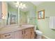 Well-lit bathroom featuring a mirror, light wood cabinets, and decorative artwork at 1139 Santa Cruz Dr, The Villages, FL 32162