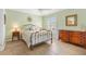 Cozy bedroom with green walls, shuttered windows, light tile flooring, and brass bed frame at 1139 Santa Cruz Dr, The Villages, FL 32162