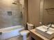 This bathroom has a shower-tub combo with glass doors, neutral tile, modern fixtures, and an elegant vanity at 3060 Rockefeller Way # 156, Kissimmee, FL 34747