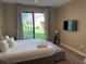 Bright bedroom with a king-size bed, tufted bench and a sliding glass door that leads to outdoor area at 3060 Rockefeller Way # 156, Kissimmee, FL 34747