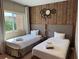 This bedroom features two twin beds, a statement wall clock, and a view to the exterior of the property at 3060 Rockefeller Way # 156, Kissimmee, FL 34747