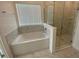 Modern bathroom with a soaking tub and a glass-enclosed shower with marble-look tile at 4910 Lyric Dr, Mascotte, FL 34753