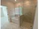 Modern bathroom featuring a glass-enclosed shower, a soaking tub, and marble-look tiling at 4910 Lyric Dr, Mascotte, FL 34753