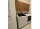 Laundry room with a modern, front-loading washer and dryer, and wooden cabinetry above at 4910 Lyric Dr, Mascotte, FL 34753