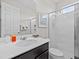 Bathroom featuring a large sink with black cabinetry, a mirror, and a tiled shower behind a glass door at 9001 Flamingo Key Way, Kissimmee, FL 34747