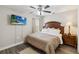 Bedroom with a wooden bed frame, ceiling fan, mounted TV, side table and lamp at 2710 Manesty Ln, Kissimmee, FL 34747