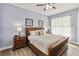 Cozy bedroom features a wooden bed frame, side table with lamp, and a ceiling fan at 2710 Manesty Ln, Kissimmee, FL 34747